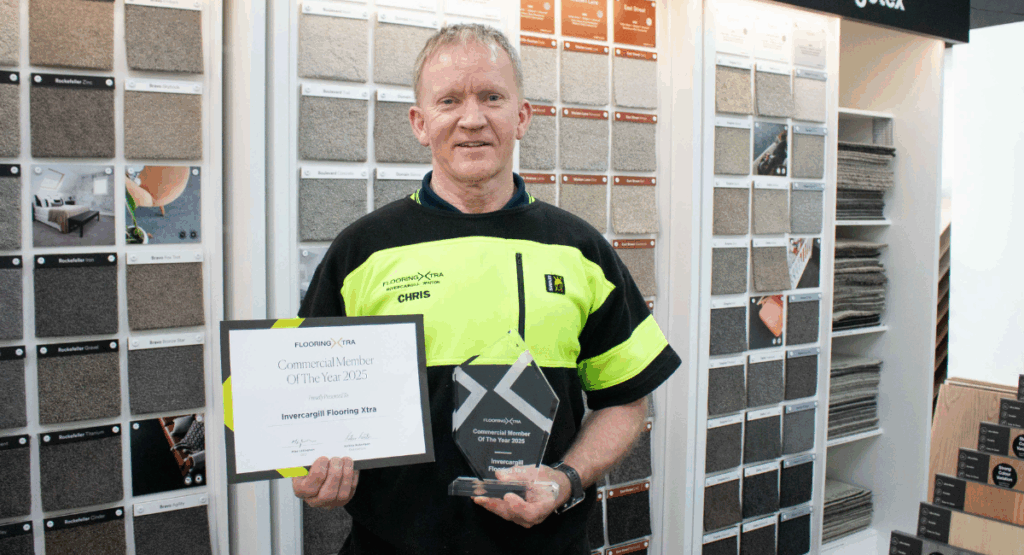 Chris from Flooring Xtra Invercargill and Winton holding a trophy for Commercial member of the year 2025
