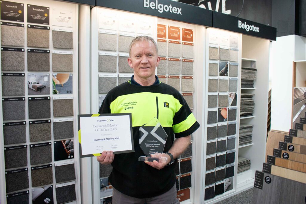 Chris from Flooring Xtra Invercargill and Winton holding a trophy for Commercial member of the year 2025
