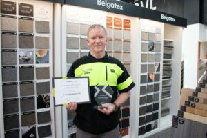 Chris from Flooring Xtra Invercargill and Winton holding a trophy for Commercial member of the year 2025