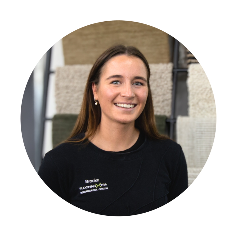 Brooke whos is a young female flooring consultant standing in front of carpet samples smiling