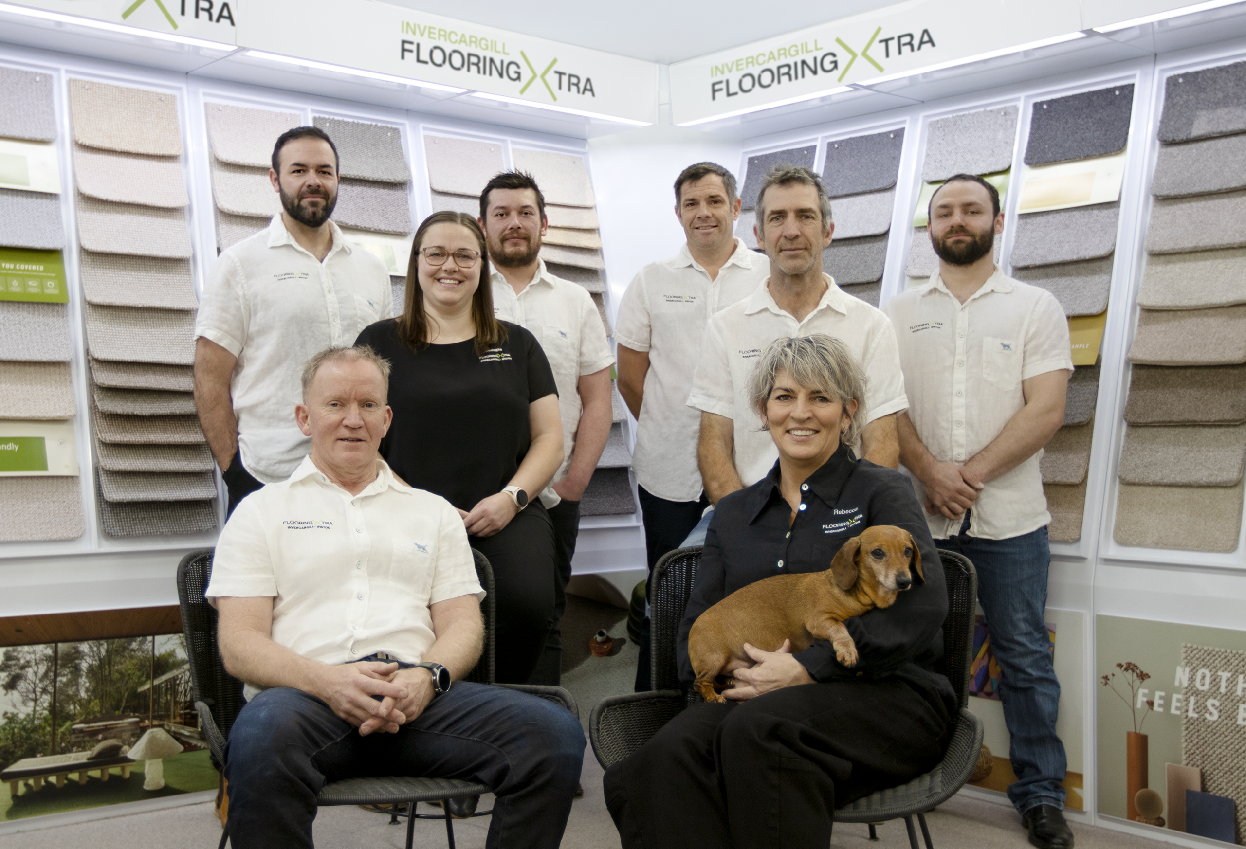 The shareholders of Invercargill and Winton Flooring Xtra all standing in front of wool carpet samples smiling