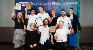 The Invercargill and Winton Flooring Xtra team standing in front of a backdrop that says Excellence in Flooring Awards holding their awards and trophies won